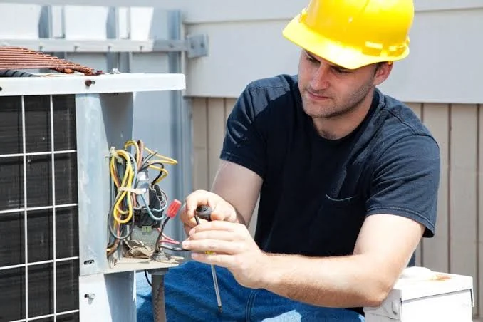 HVAC technician diagnosing controls on a residential cooling system