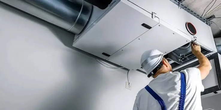 Technician servicing an indoor HVAC air handling unit