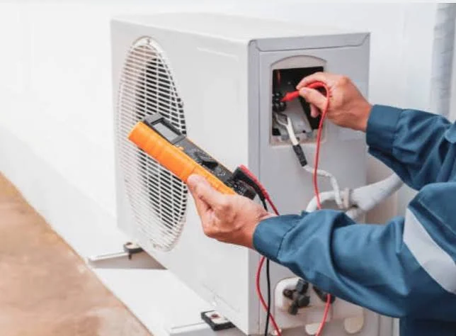Technician checking HVAC electrical voltage with a digital meter