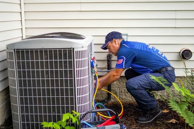 Technician connecting service gauges to a residential condenser