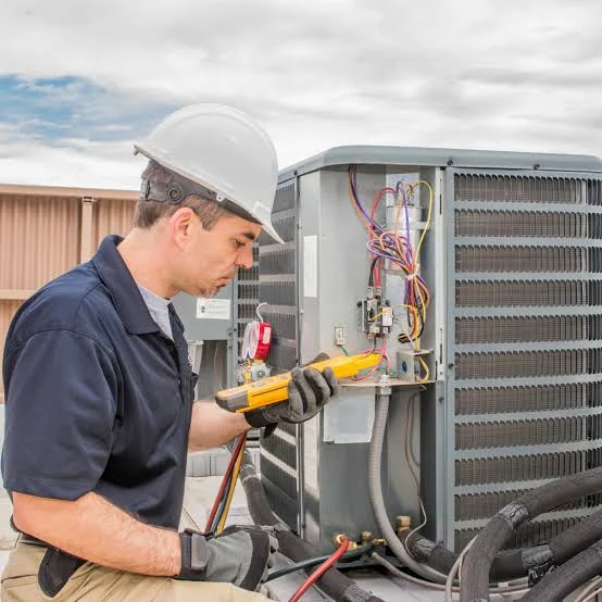 HVAC technician testing electrical components on an outdoor condenser